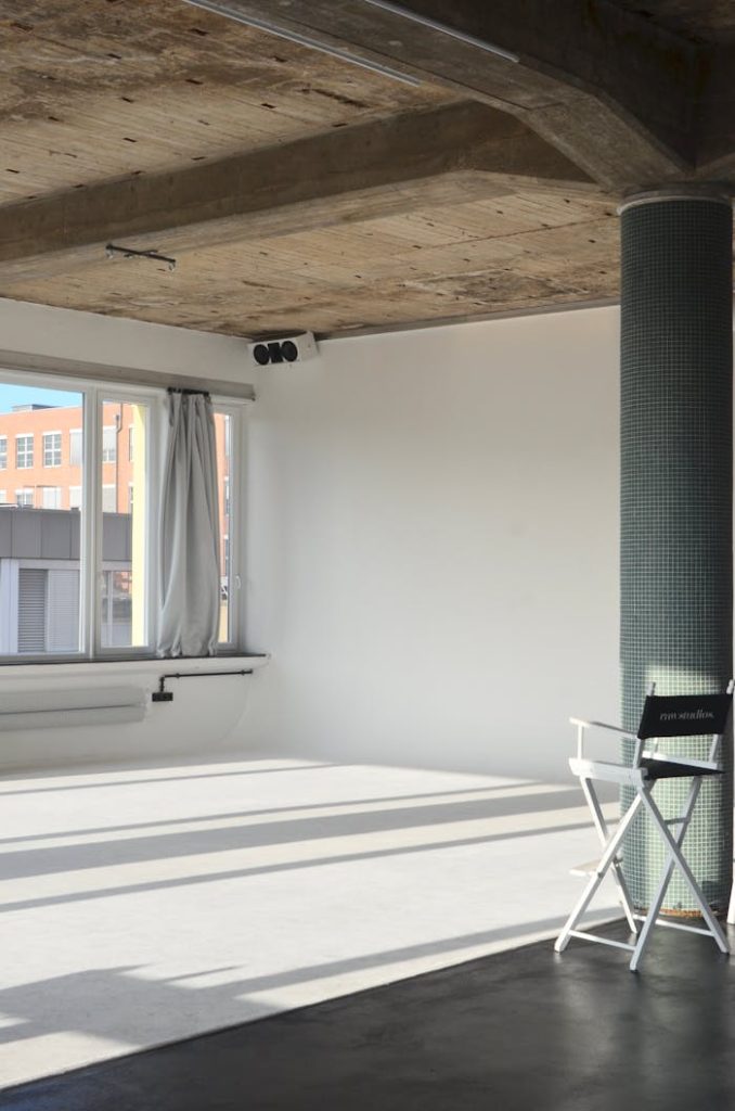 Spacious modern loft with natural light and minimalist design featuring a white chair and pillar.